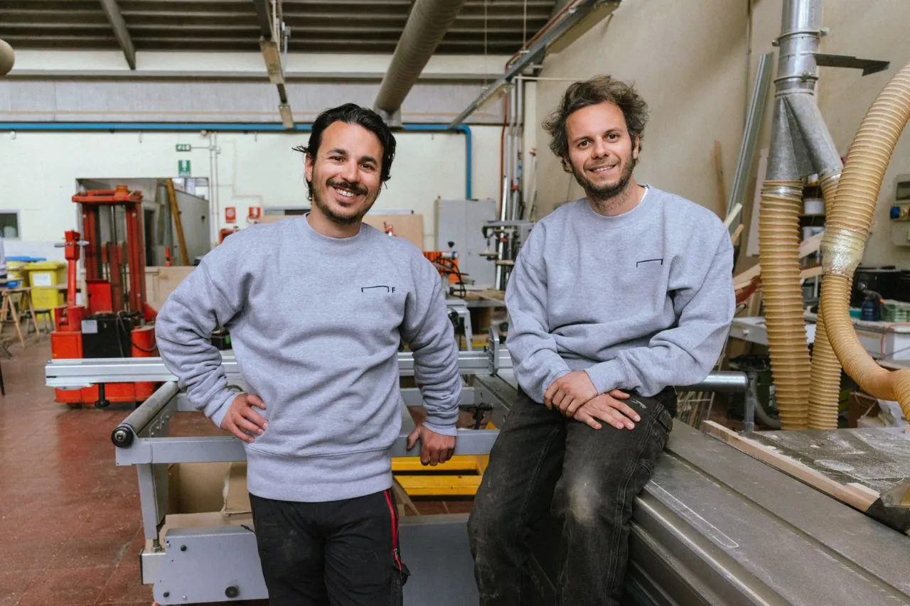 Dos carpinteros sonriendo con su uniforme de trabajo